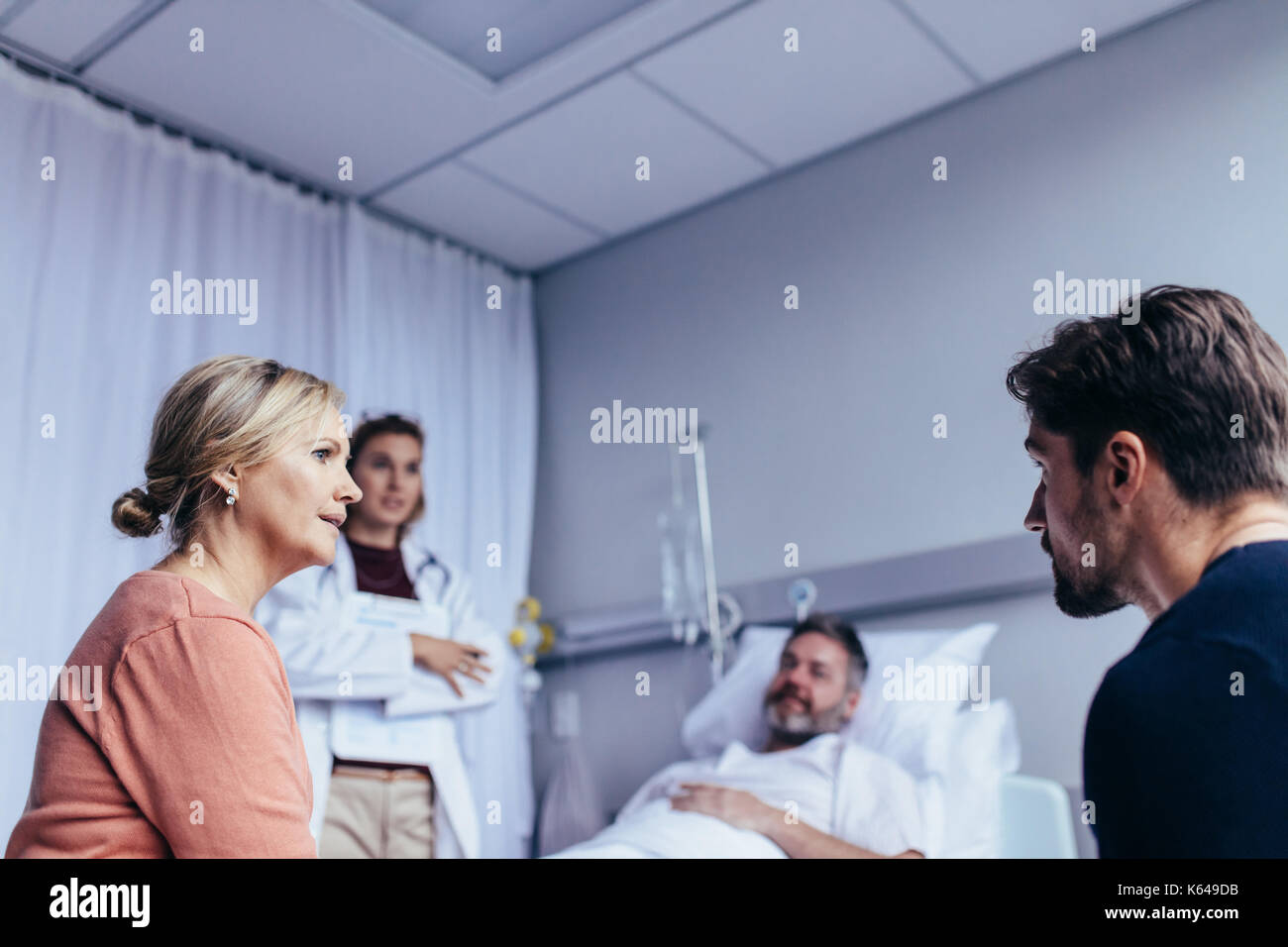 Familie in der Krankenstation mit Mann im Bett und Arzt liegen bereit. Familie Besuch im Krankenhaus Mann im Gefängnis. Stockfoto