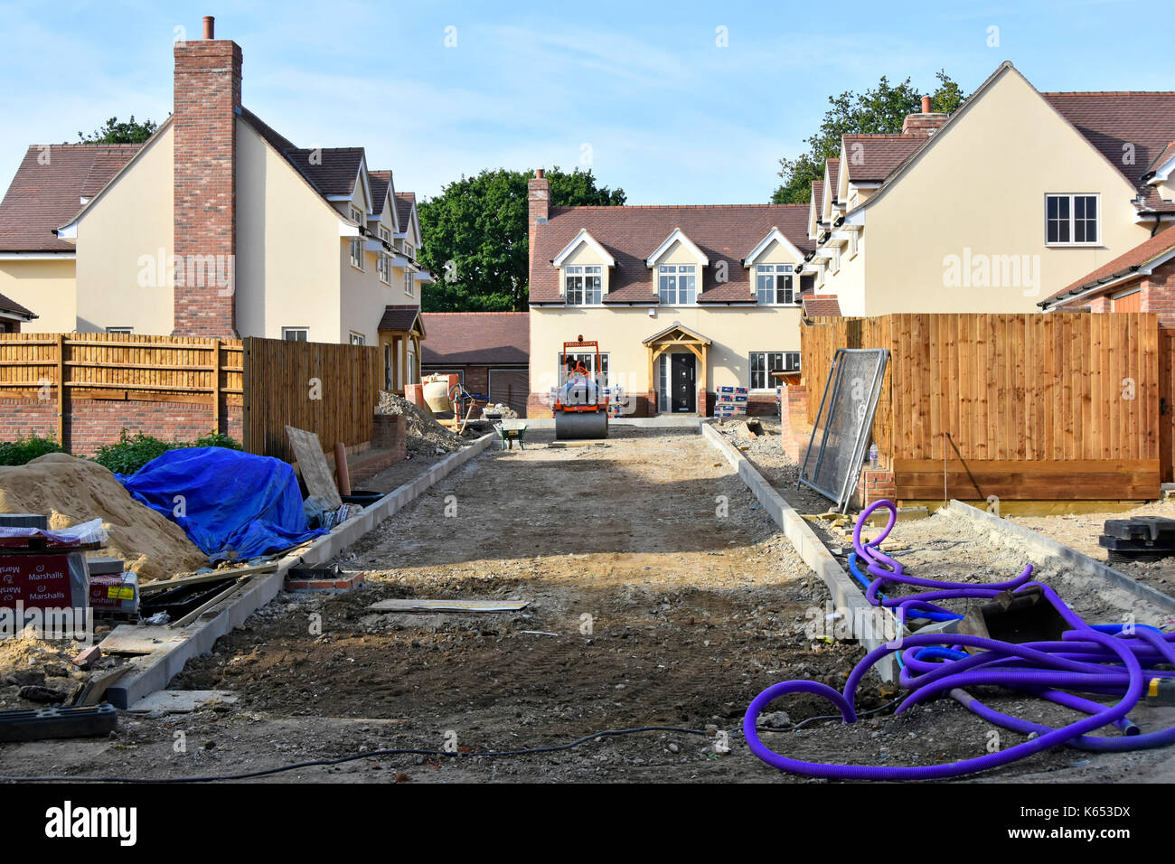 Baustelle für neue kleine Wohneigentum Entwicklung kurz vor dem Abschluss mit Aufkantungen Gartenzäune und Straße Stiftungen in Fortschritte Essex England Großbritannien Stockfoto