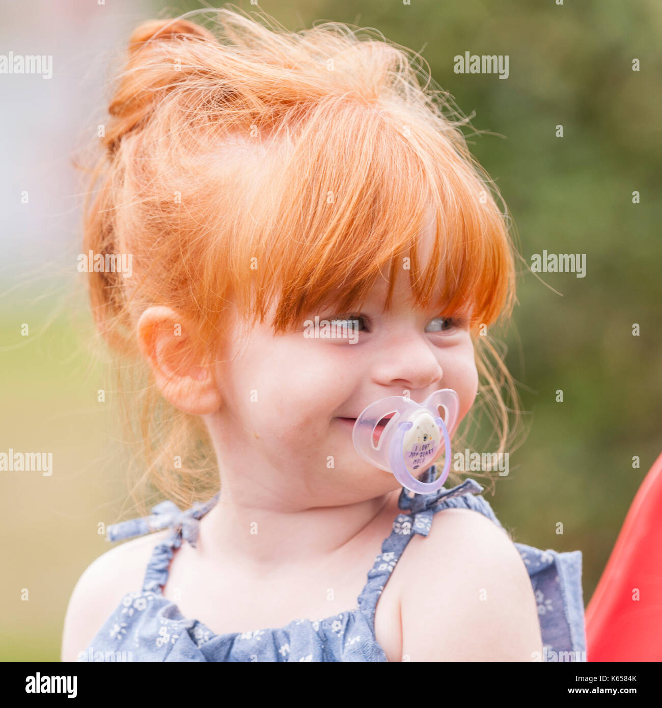Ein MODEL RELEASED 2 Jahre altes Mädchen mit Ingwer Haar und ein Dummy im Freien in Großbritannien Stockfoto