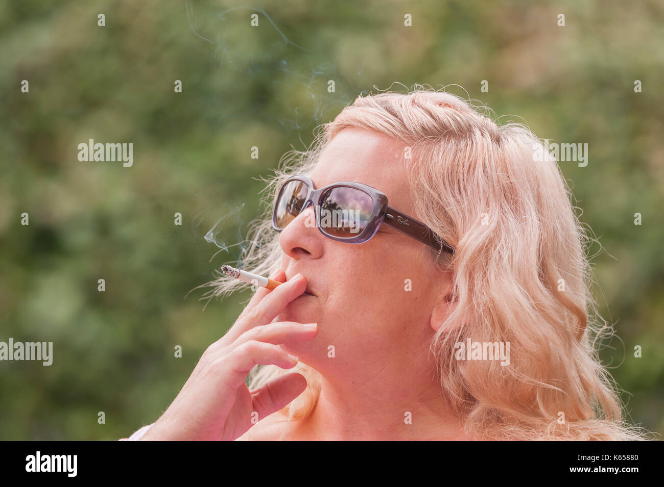 Ein MODEL RELEASED Frau in den 40er Jahren das Rauchen einer Zigarette im Freien in Großbritannien Stockfoto