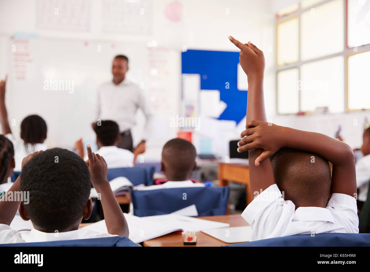 Kinder heben die Hände Lehrer an einer Volksschule Lektion zu beantworten Stockfoto