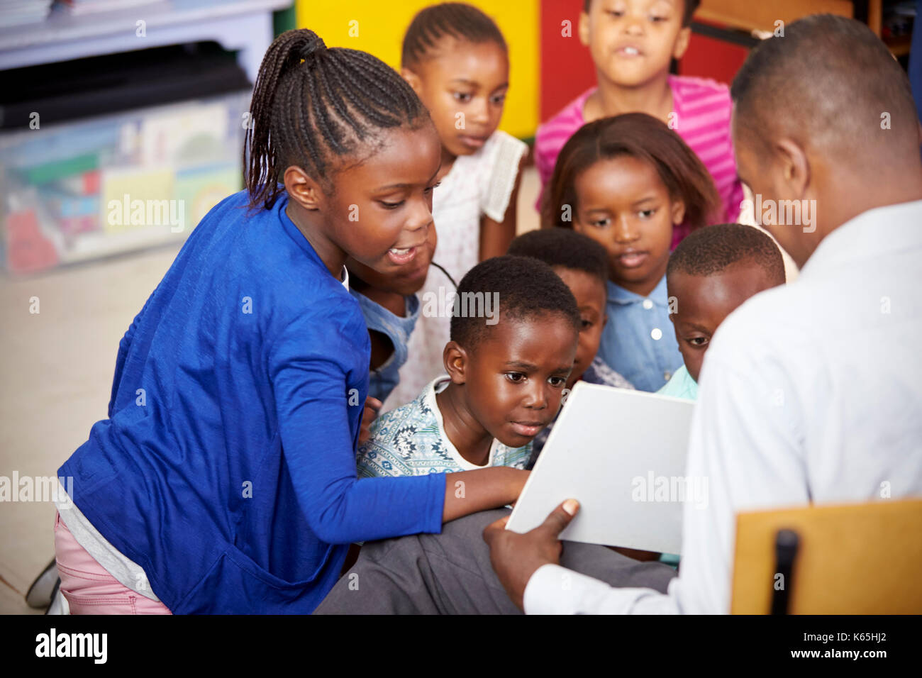 Lehrer zeigt den Kindern ein Buch während der Volksschule Lektion Stockfoto