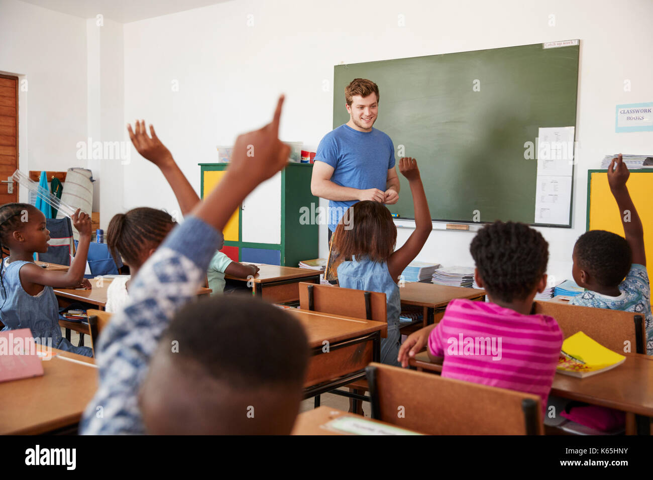 Kinder heben die Hände zu Lehrer in einer Grundschule Klasse Stockfoto