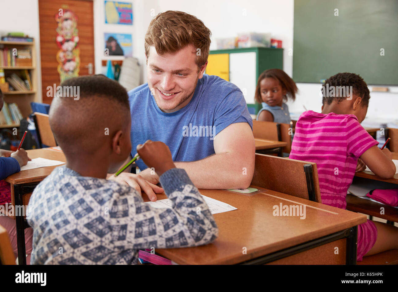 Weiße männliche Lehrer helfen Volksschule Junge in der Klasse Stockfoto
