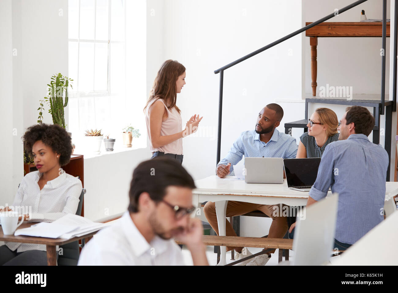 Die Kollegen in der Diskussion um einen Schreibtisch im Großraumbüro Stockfoto