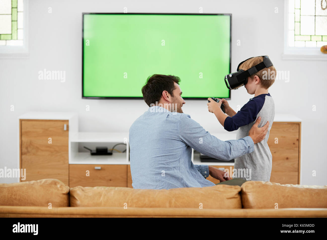 Vater und Sohn spielen Computer Spiel mit Virtual Reality Headset Stockfoto