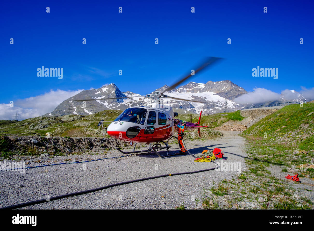 Ein Mitarbeiter der Firma Swiss Helicopters betankt den Hubschrauber für den Transport von Beton zu einer Baustelle in den Bergen von Bernina aus Stockfoto