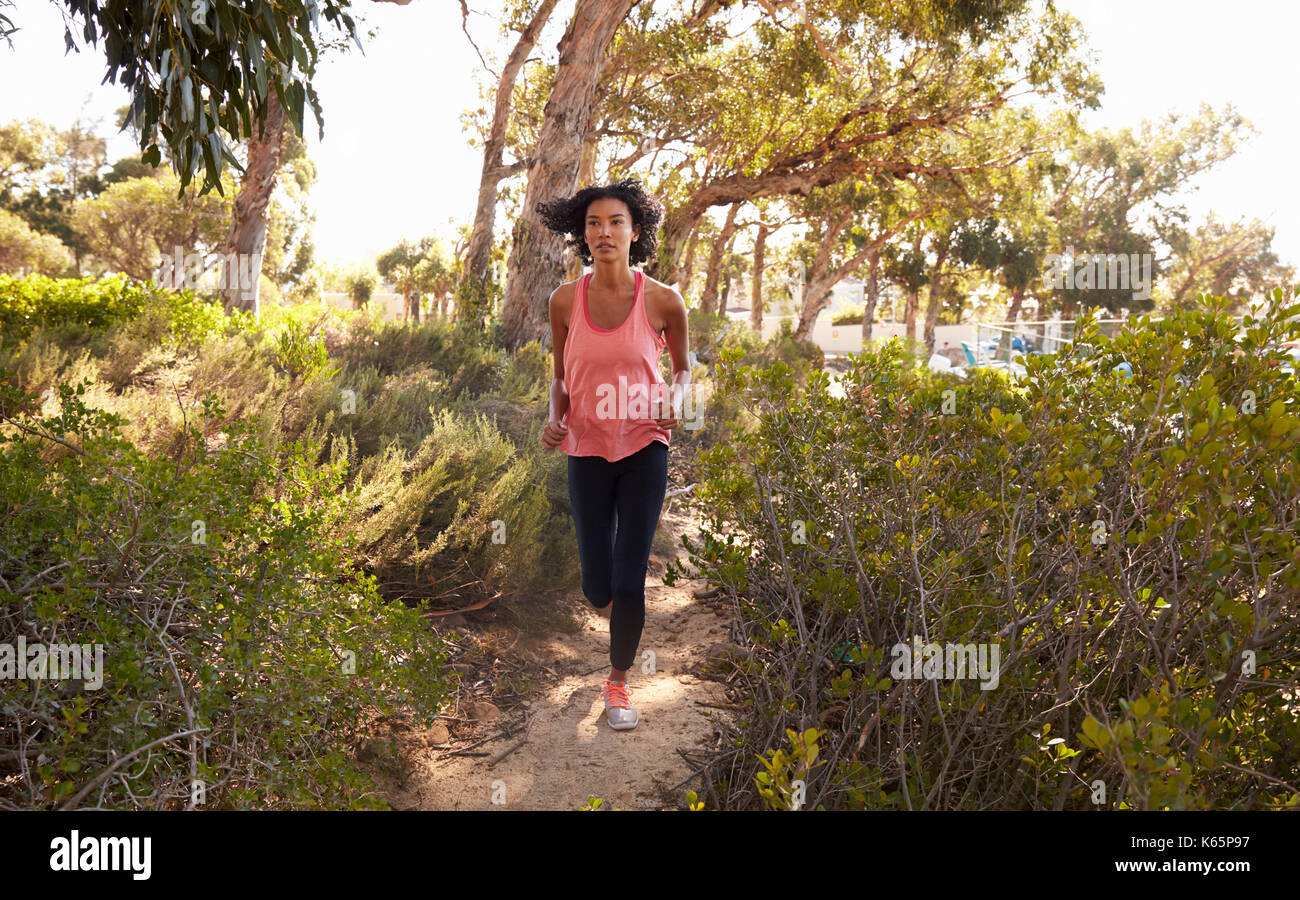 Junge schwarze Frau durch einen Wald läuft Stockfoto