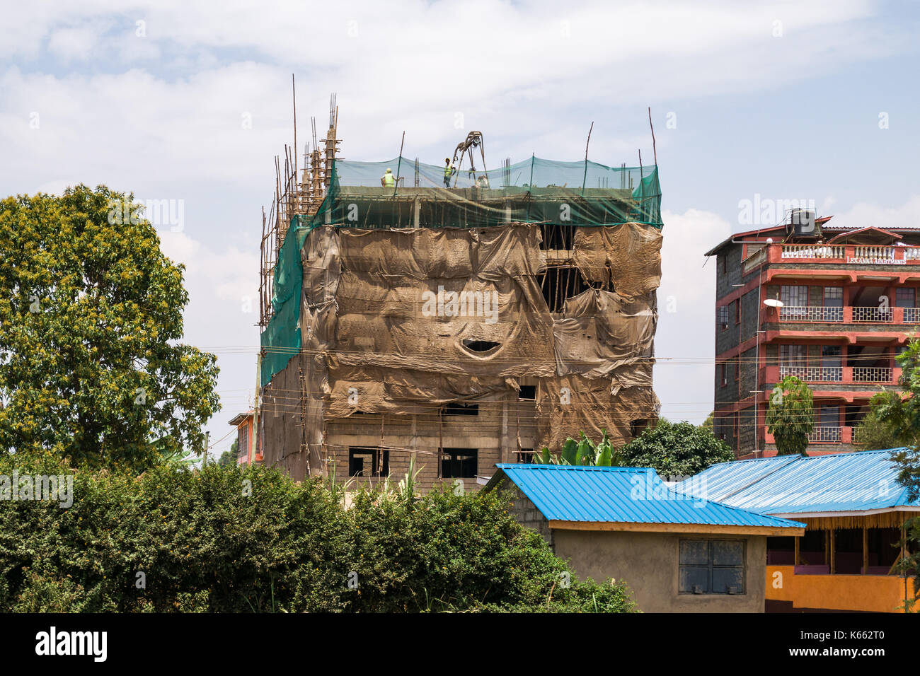 Appartementhaus im Bau mit Bauarbeiter auf dem Dach in der kleinen Stadt, Kenia Stockfoto