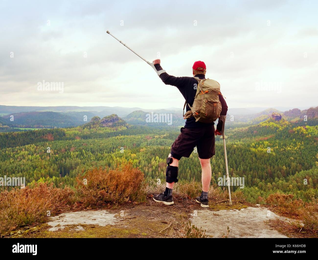 Peak Triumph. Mann mit Bein in Knie Käfige und Krücken für Stabilisierung und Unterstützung. Wanderer mit verstellbaren Seitenteile o Unterstützung zu sichern und Stockfoto