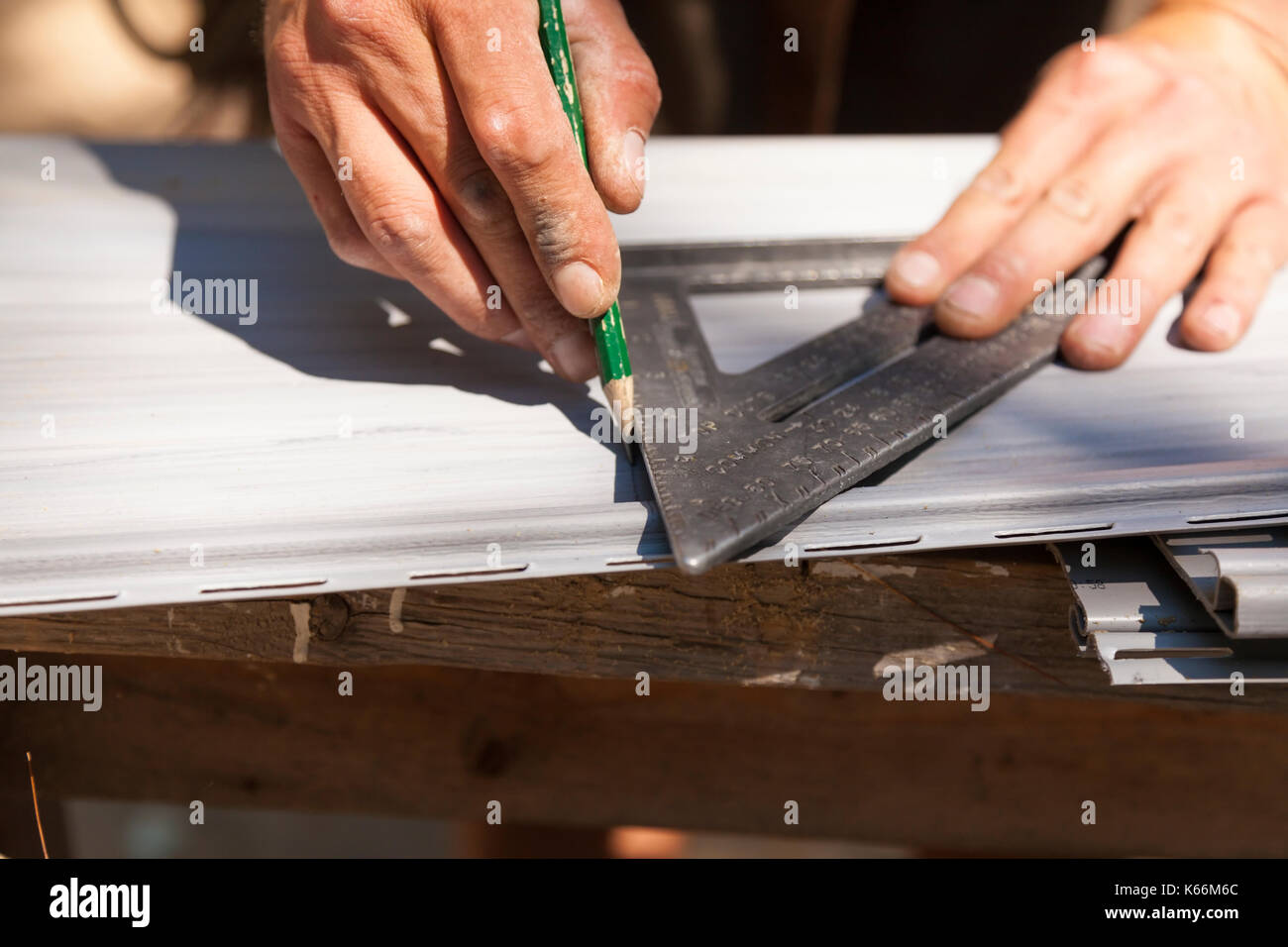 Ein Bauarbeiter Kennzeichnung Vinylabstellgleis mit einem Bleistift und einem Dreieck oder Quadrat in Ontario, Kanada. Stockfoto