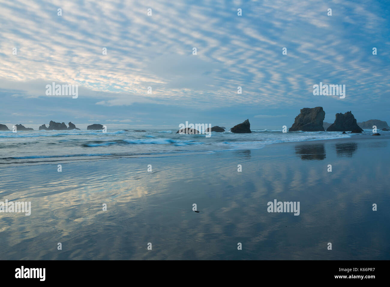 Gesprenkelte Wolken reflektieren über Bandon Strand in Oregon. USA Stockfoto