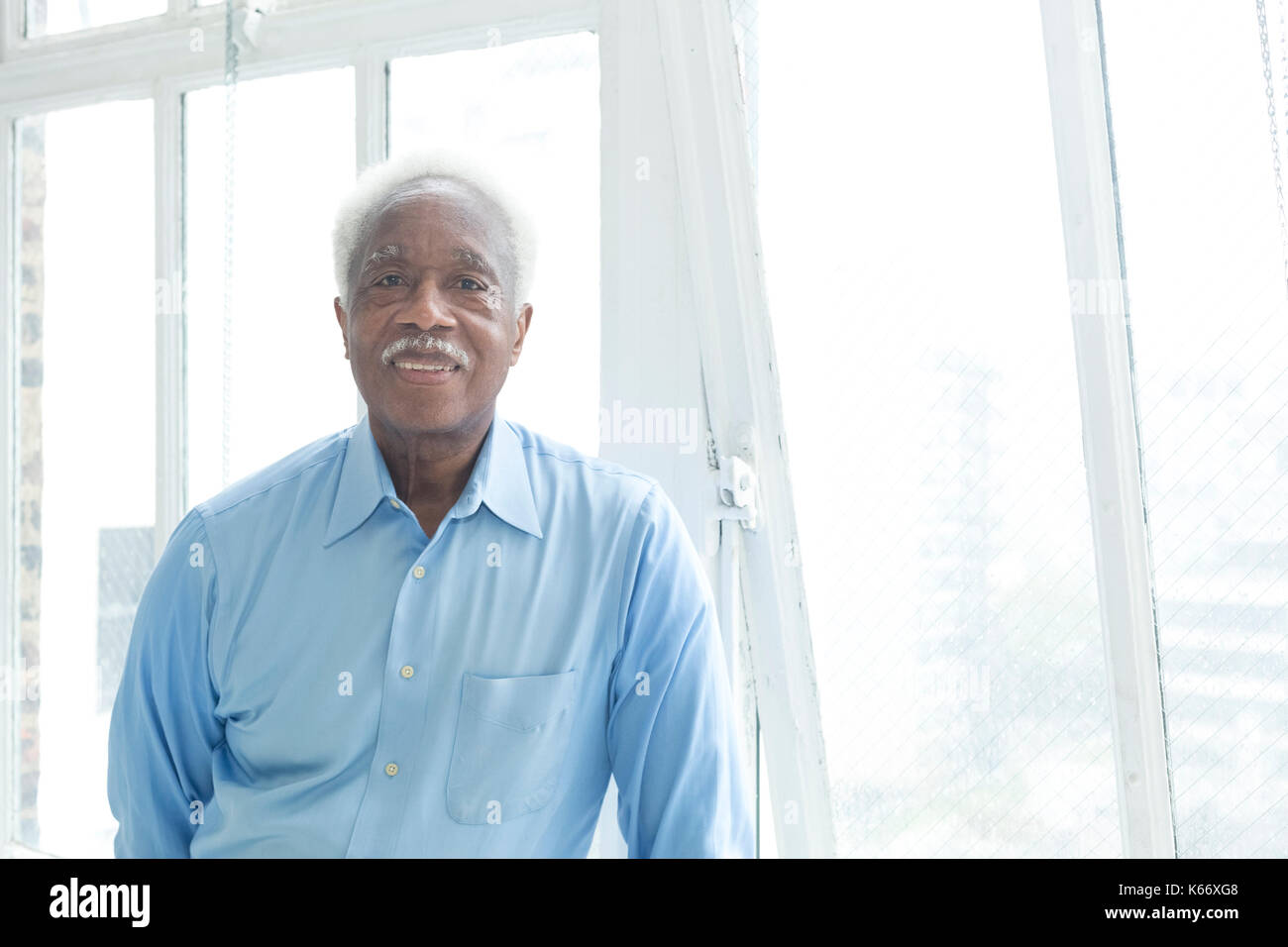 Lächelnd älteren schwarzen Mann in der Nähe der Fenster Stockfoto
