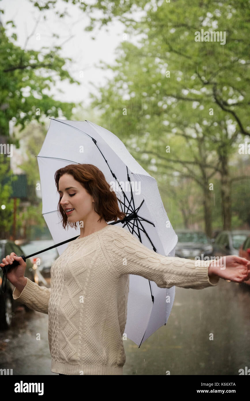 Sorglos kaukasische Frau mit Regenschirm im Regen Stockfoto