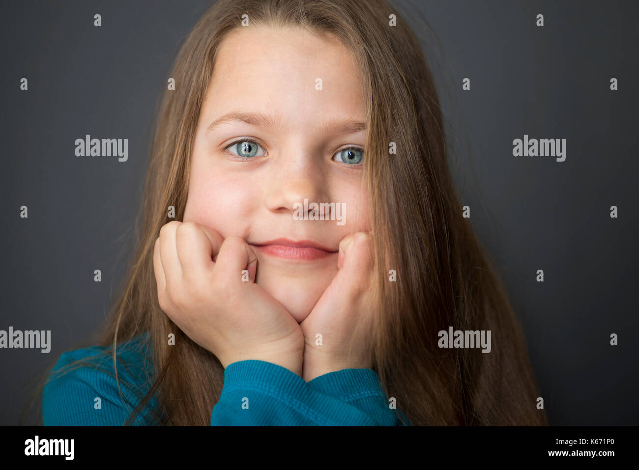 Mädchen mit weit offenen Augen, den Kopf auf die Hände Stockfoto