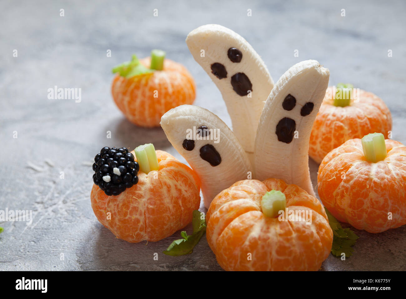 Gesunde Früchte Halloween Festlichkeiten. Banane Geister und Clementine orange Kürbisse Stockfoto