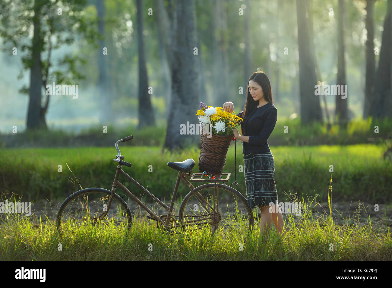 Frau mit einem Korb mit Blumen auf ihrem Fahrrad, Thailand Stockfoto
