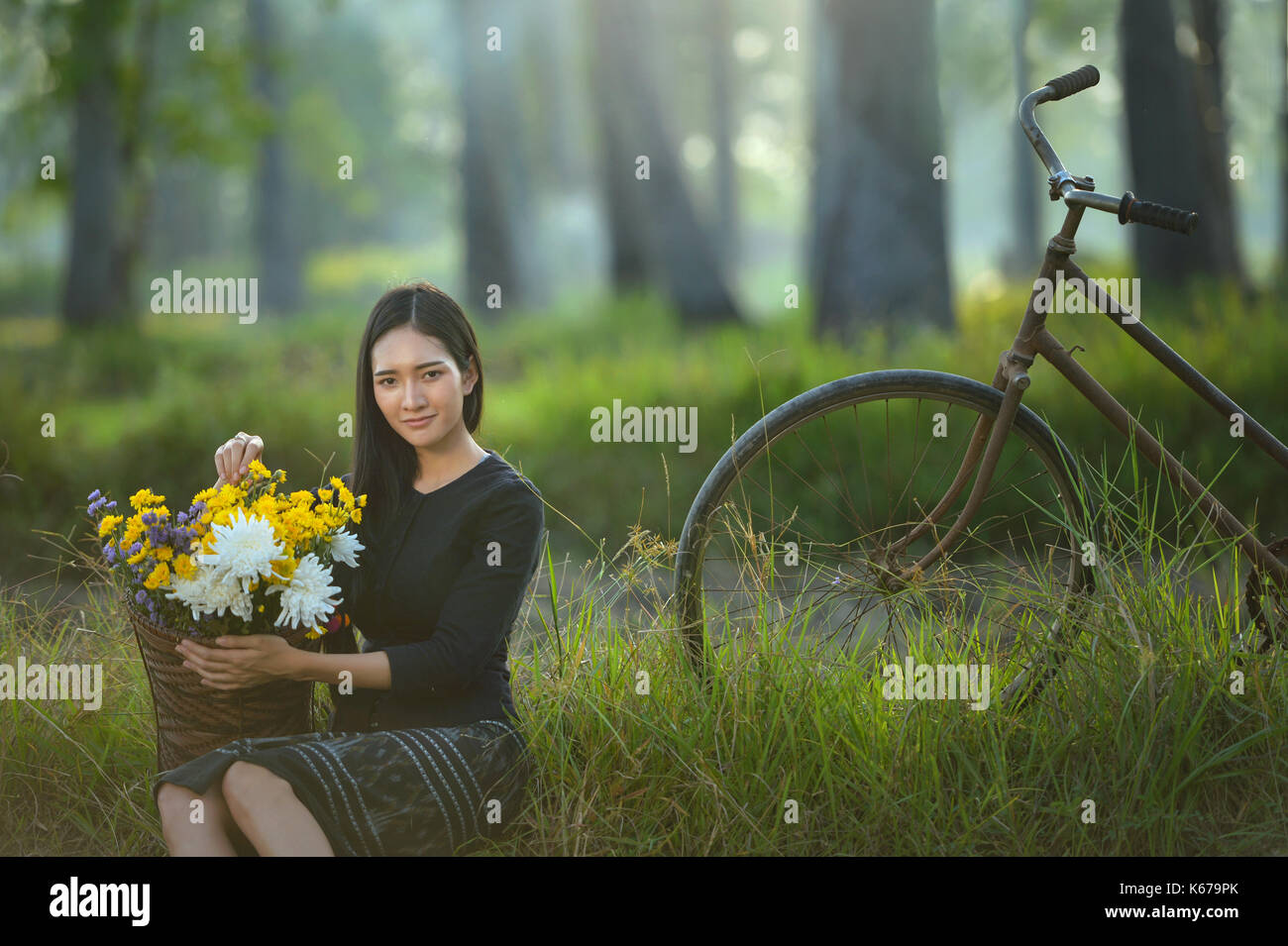Frau sitzt mit einem Korb mit Blumen, Thailand Stockfoto
