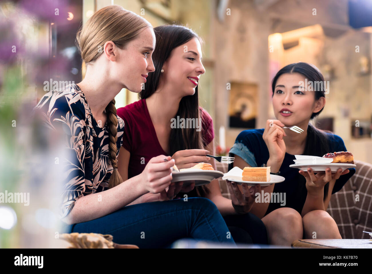 Drei junge Frauen Kuchen Essen drinnen Stockfoto