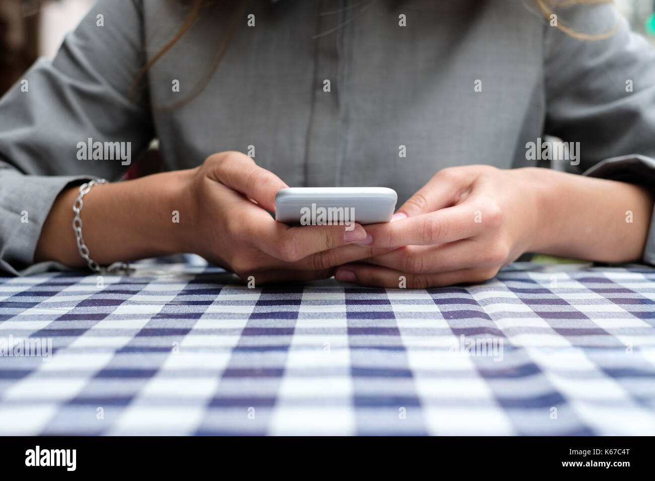 Frau sitzt an einem Tisch mit Ihrem Mobiltelefon Stockfoto