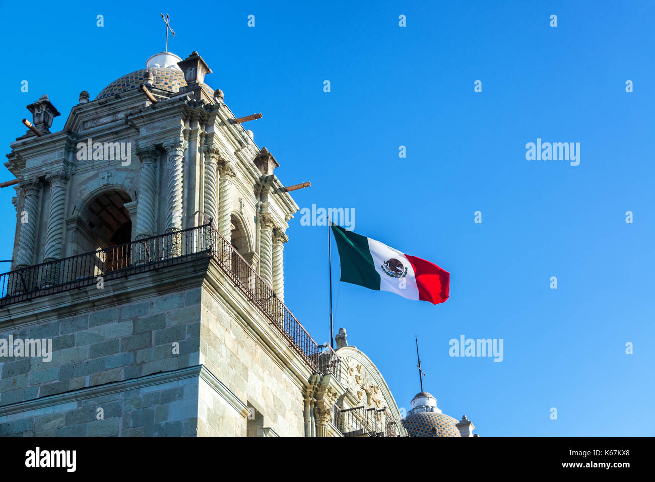 Mexikanische Flagge über Unsere Liebe Frau Mariä Himmelfahrt Kirche in Oaxaca, Mexiko am 4. März 2017 fliegen Stockfoto