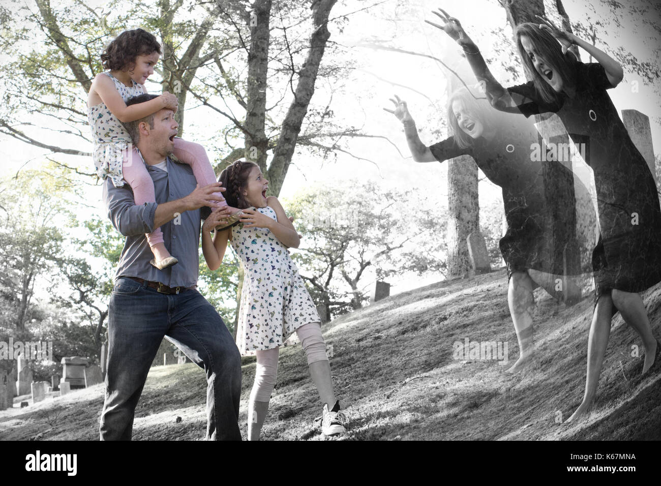 Eine Familie in einem Friedhof sieht einen furchtsamen Geist einer Frau Stockfoto