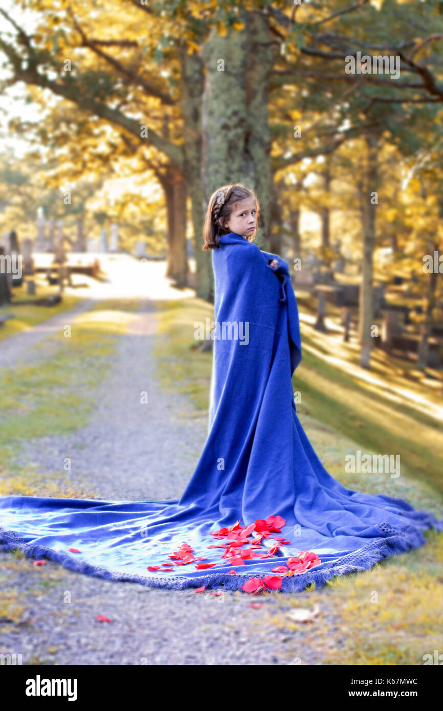 Ein junges Mädchen in einer Decke eingewickelt mit Rosen sieht auf dem Friedhof traurige Stockfoto