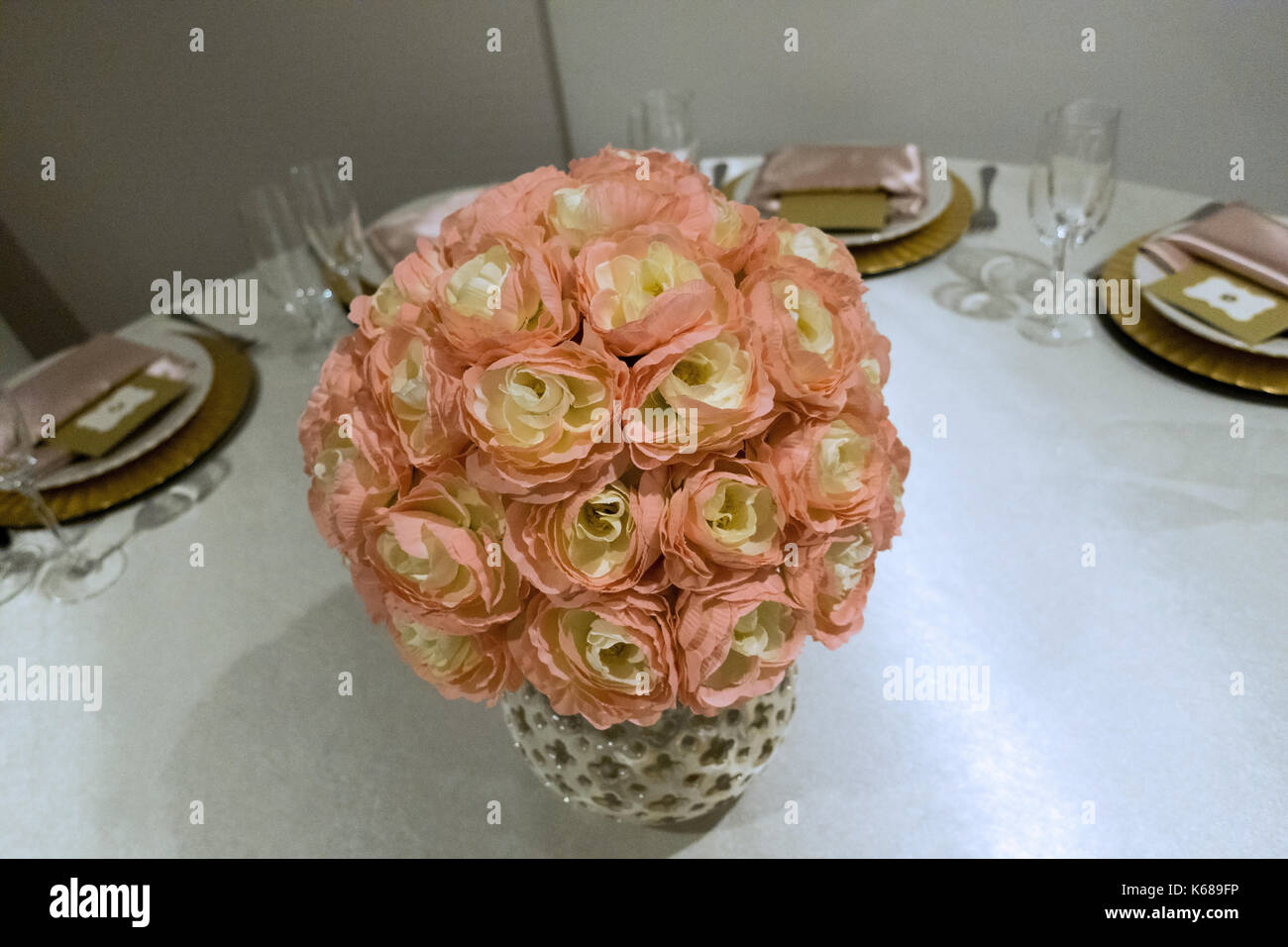 Ein rosa Vase mit Blumen in der Mitte einer Tabelle für geladene Gäste eingestellt. Stockfoto