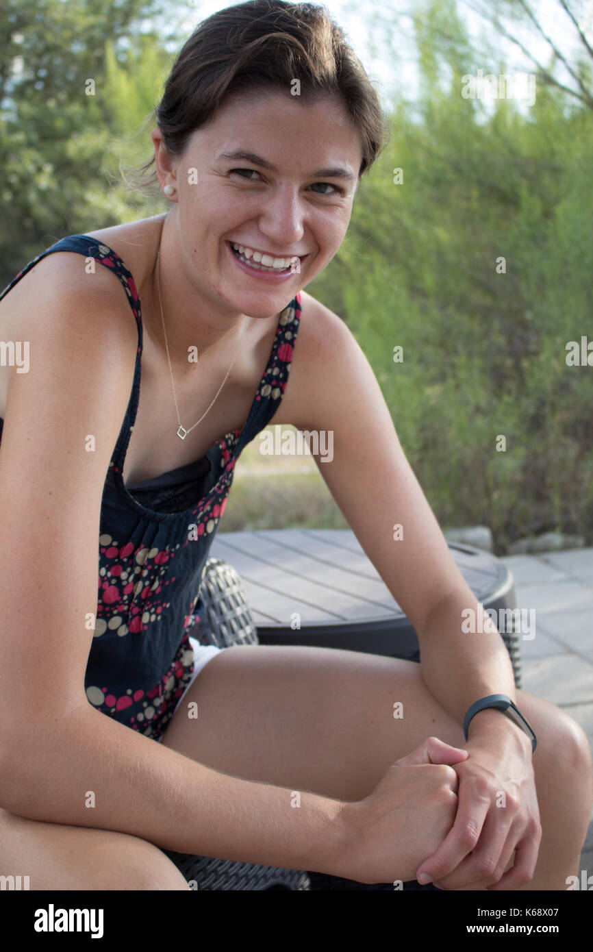 Junges Mädchen mit dunklen Haaren zog zurück in einem Brötchen im Freien im Sommer lächelnd Stockfoto