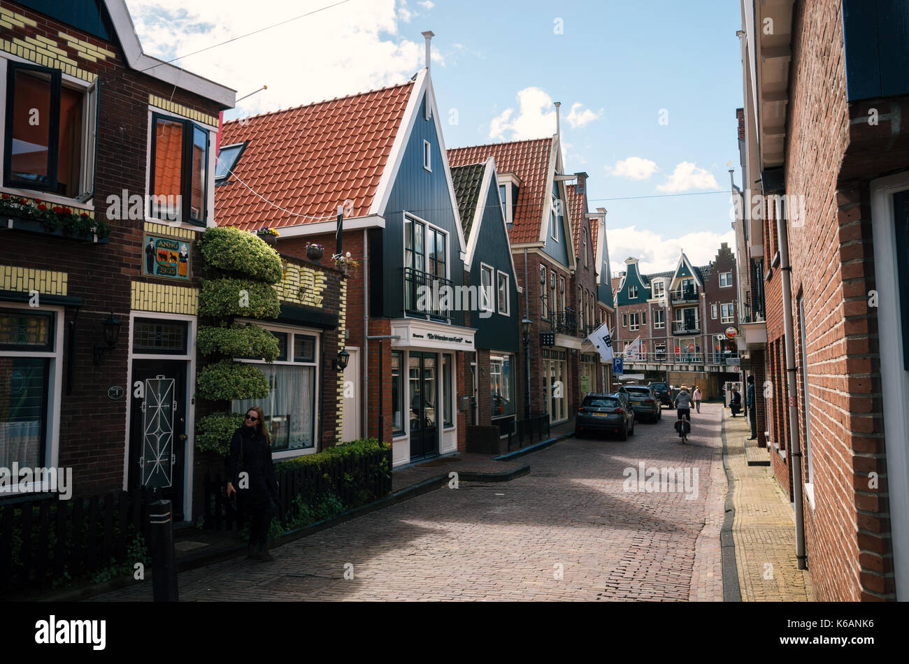 Volendam, Niederlande - 26. April 2017: Bewohner von Dorf Volendam mit dem Fahrrad vor den typischen traditionellen Häuser von einem niederländischen Fischerei Vill Stockfoto
