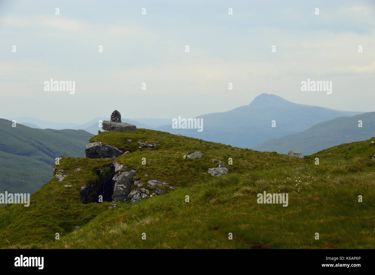 Ein Cairn auf einem Felsen über dem Glen Croe und die Scottish Mountain Munro Ben Lomond aus dem Corbett Ben Dornich im Glen Croe, Westschottland. Stockfoto