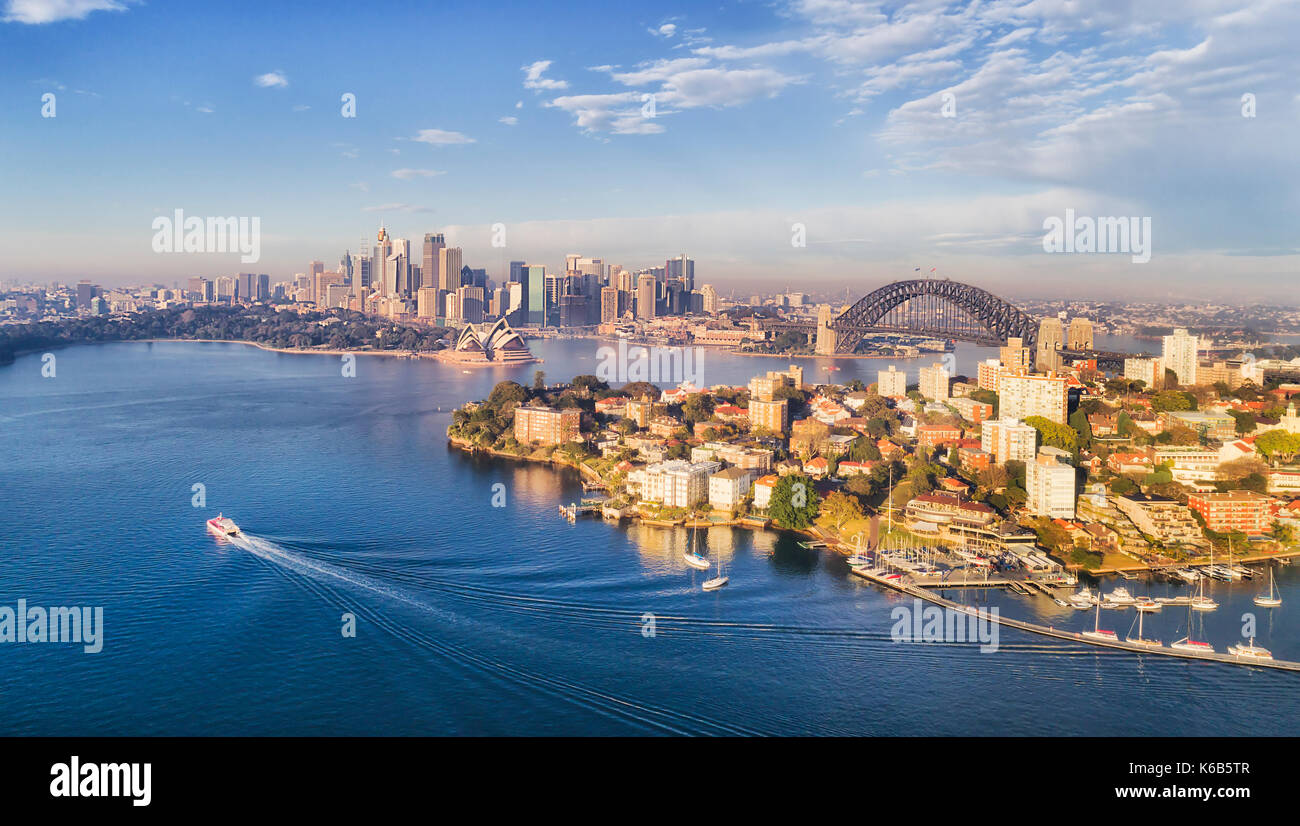Kirribilli Yacht Club, Strand und Jachthafen vor Stadt Sydney CBD, die Harbour Bridge und Grenzsteine um Gewässer des Hafens von Sydney unter warmen mornin Stockfoto