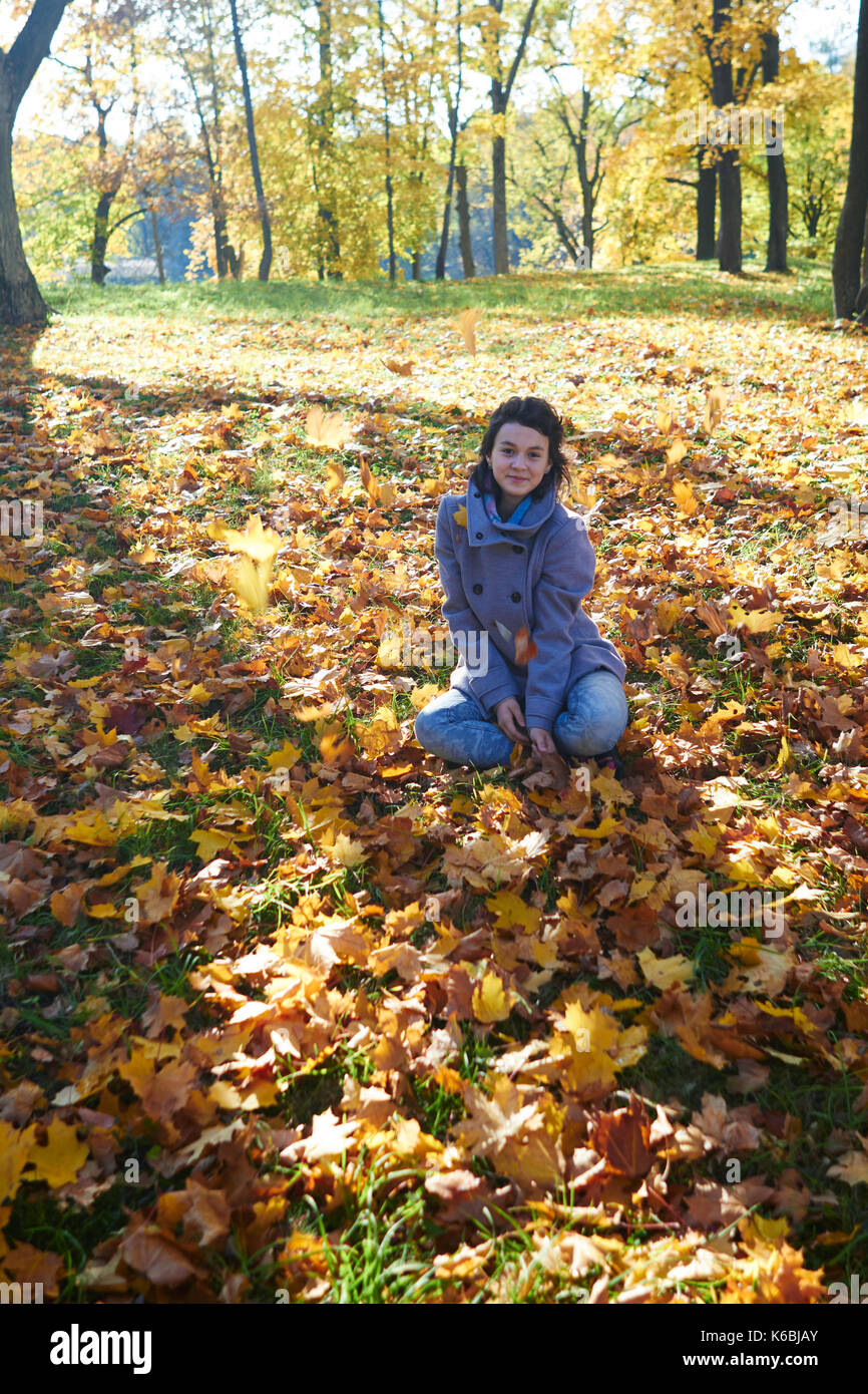 Glückliche junge jugendlich Mädchen im Herbst Landschaft werfen Blätter Stockfoto