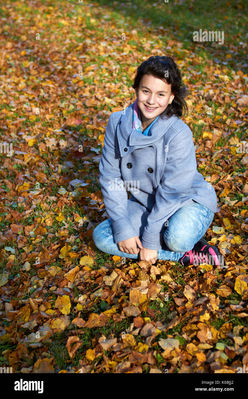 Glückliche junge jugendlich Mädchen im Herbst Landschaft werfen Blätter Stockfoto