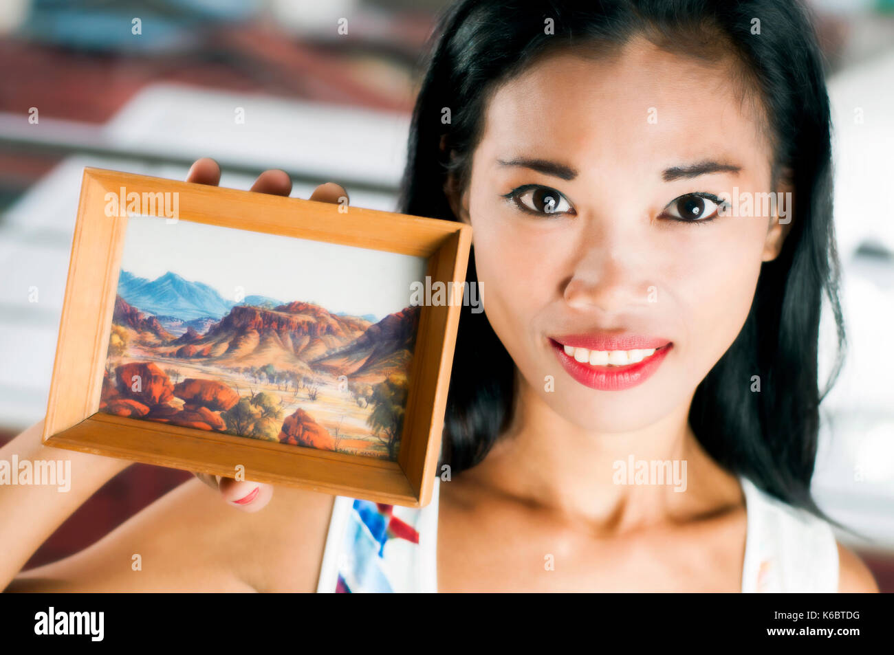 Junge asiatische Frau mit kleinen retro Reproduktion von Albert Namatjira Malerei in innere Einstellung, Cebu, Philippinen Stockfoto