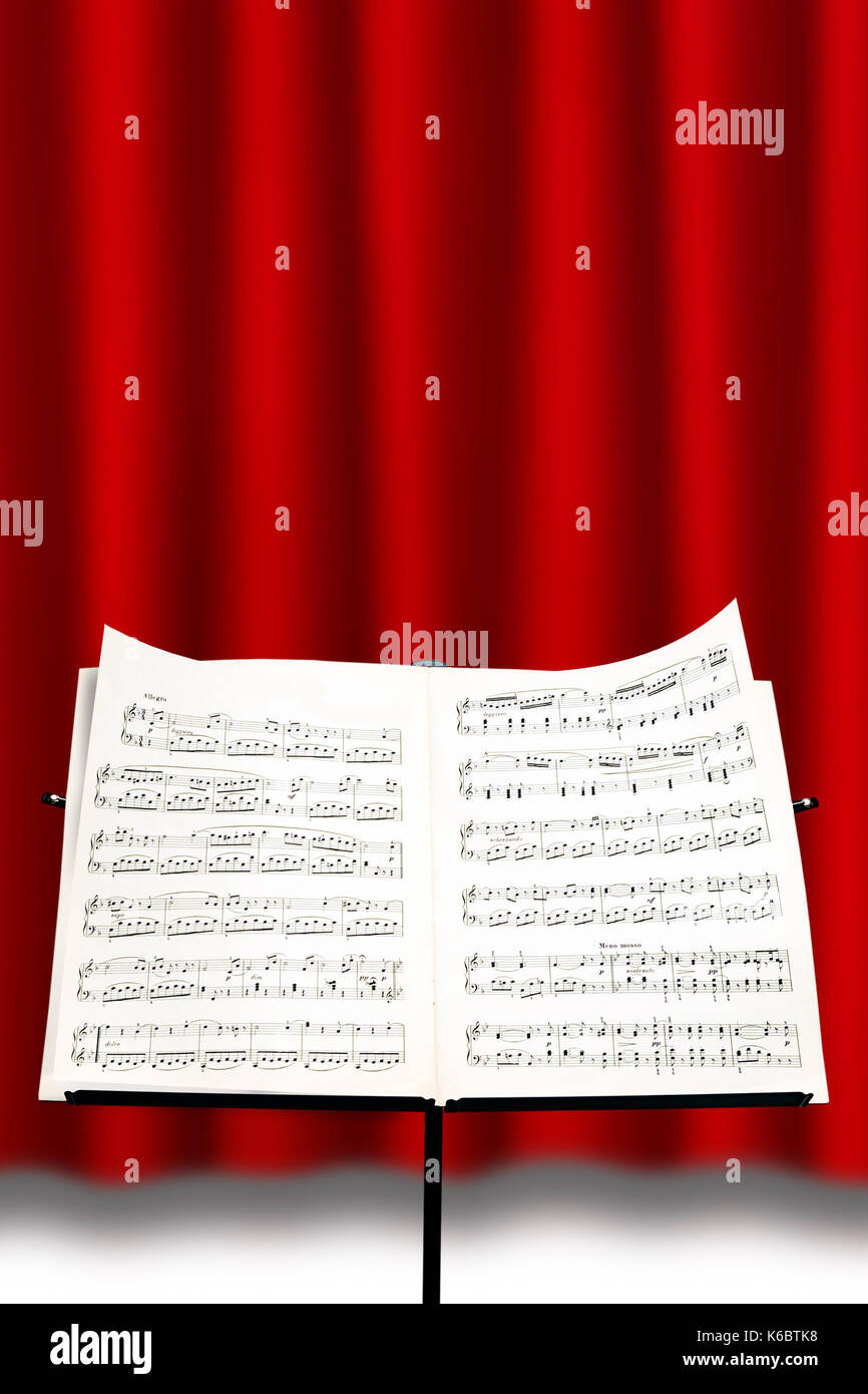 Notenständer mit einer Partitur vor einem roten Vorhang Stockfoto