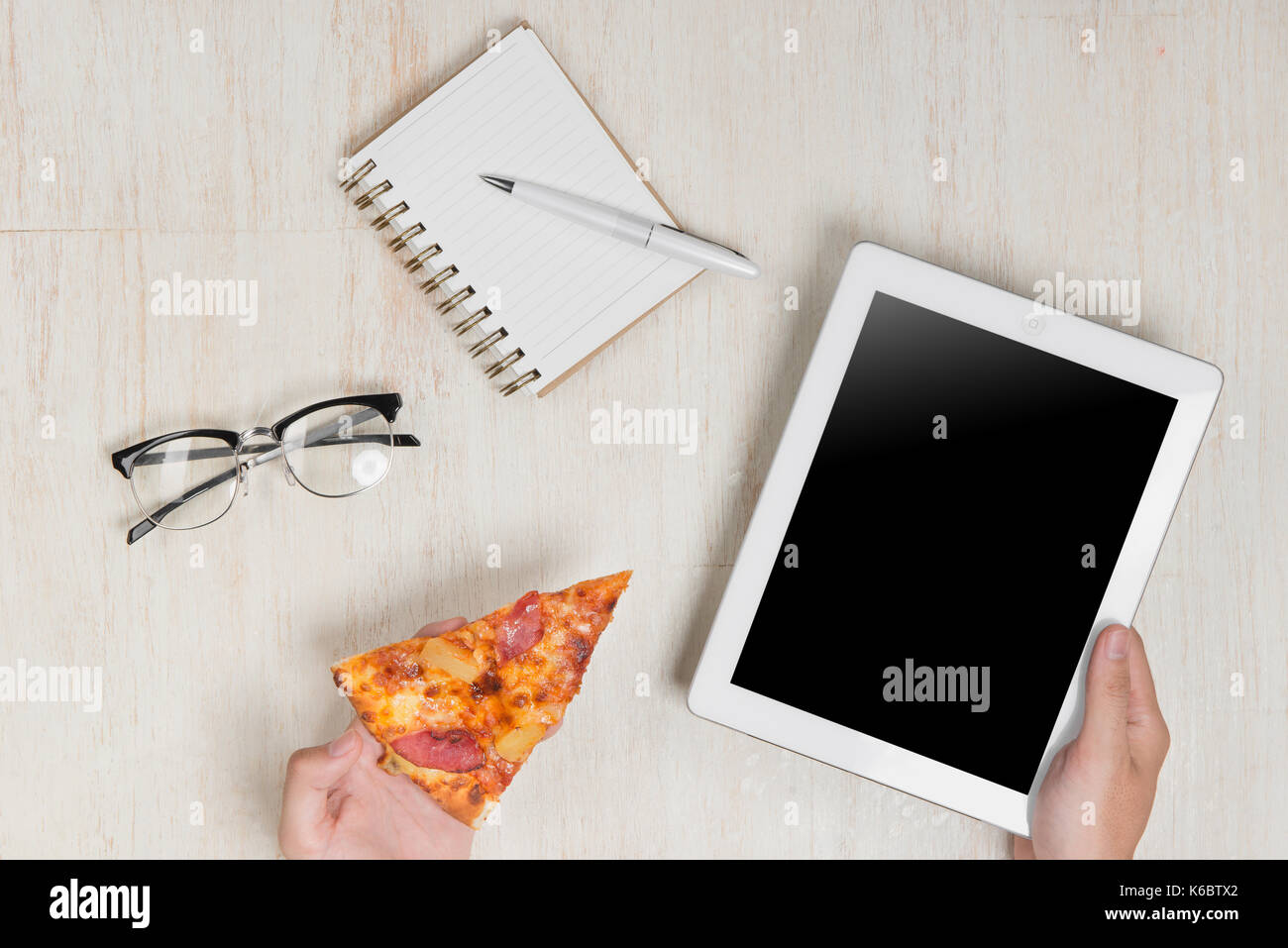 Mann hält eine digitale Tafel- und leckere Pizza mit Zutaten aus hölzernen Tisch. Stockfoto