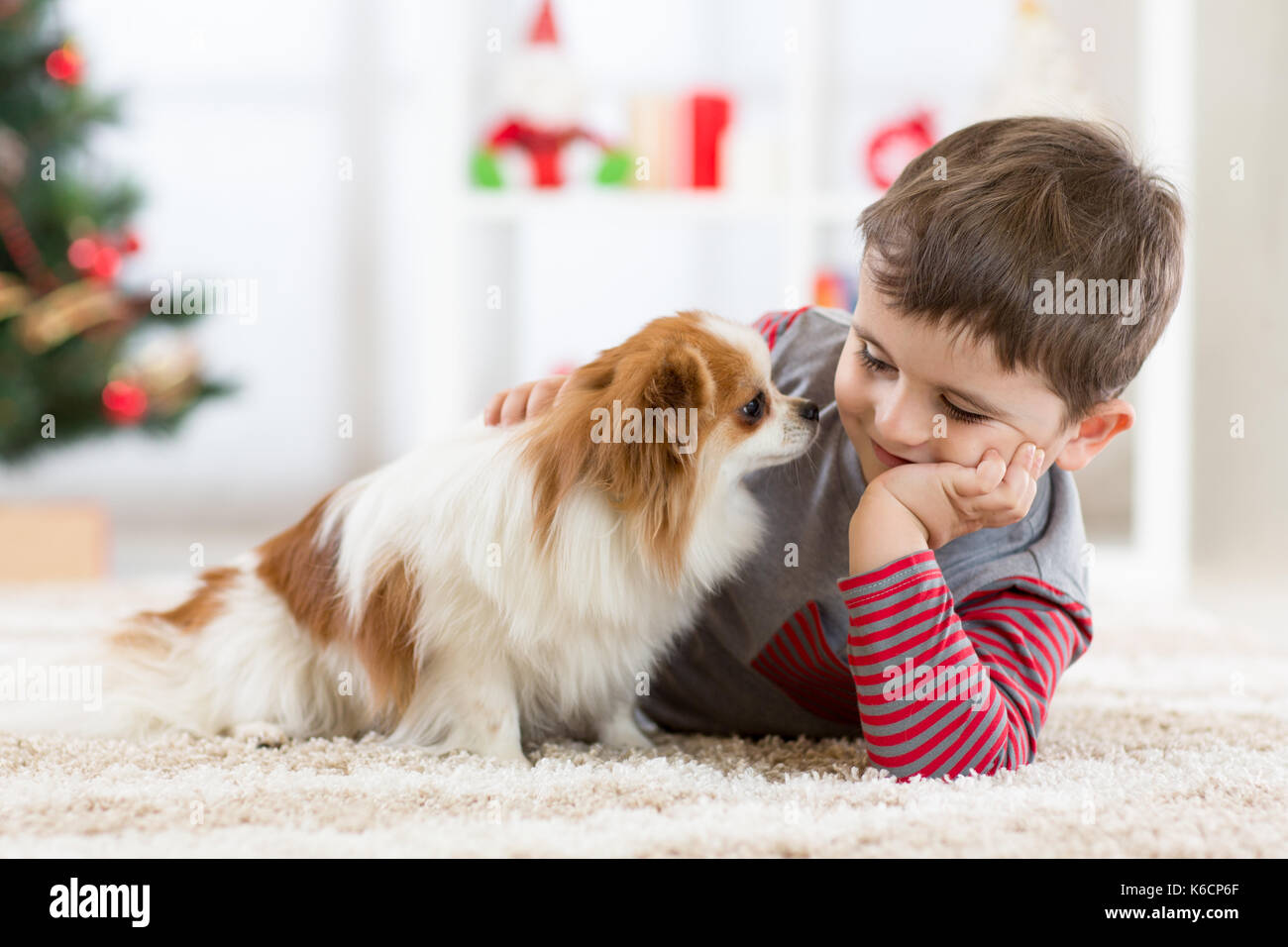 Little Baby Junge mit Hund liegend auf dem Boden Weihnachtsbaum Stockfoto