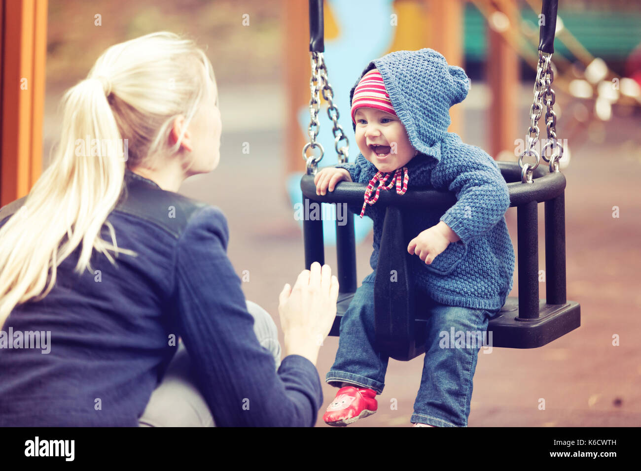 Mutter mit ihrem Kind Spaß auf dem Spielplatz schwingen auf Herbst Tag Stockfoto