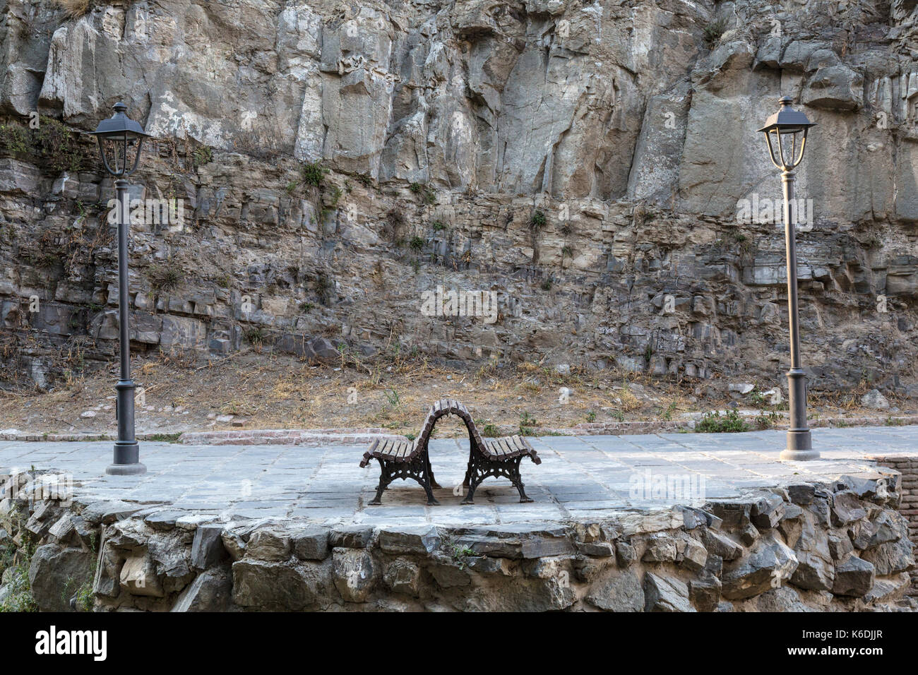 Zwei Gusseisen Bänke, Rücken an Rücken, und zwei gusseisernen Strassenlaternen auf einer Straße in Tiflis, Georgien. Stockfoto