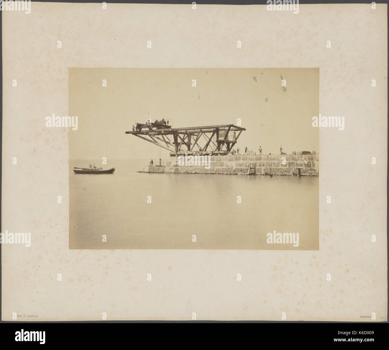 Ein historisches Foto, das den Bau eines Hafendamms an der Mündung des Nordseekanals zeigt und eine Seitenansicht der Kraninstallation während des Bauvorgangs zeigt. Stockfoto