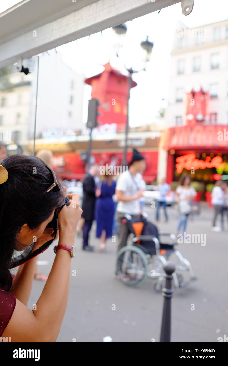 Ein Tourist nimmt ein Foto der Massen außerhalb des Moulin Rouge in Montmartre, Paris Stockfoto