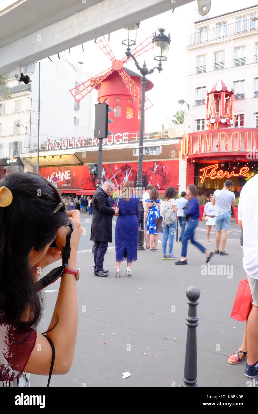 Ein Tourist nimmt ein Foto der Massen außerhalb des Moulin Rouge in Montmartre, Paris Stockfoto