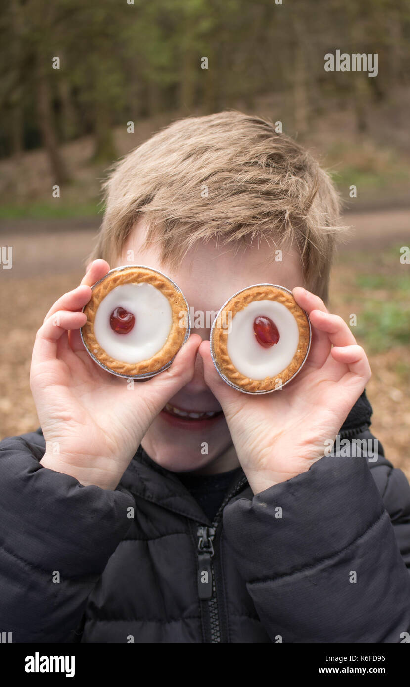 Junge spielt mit Bakewell Torten während auf Picknick vortäuschen, dass sie Augen Stockfoto