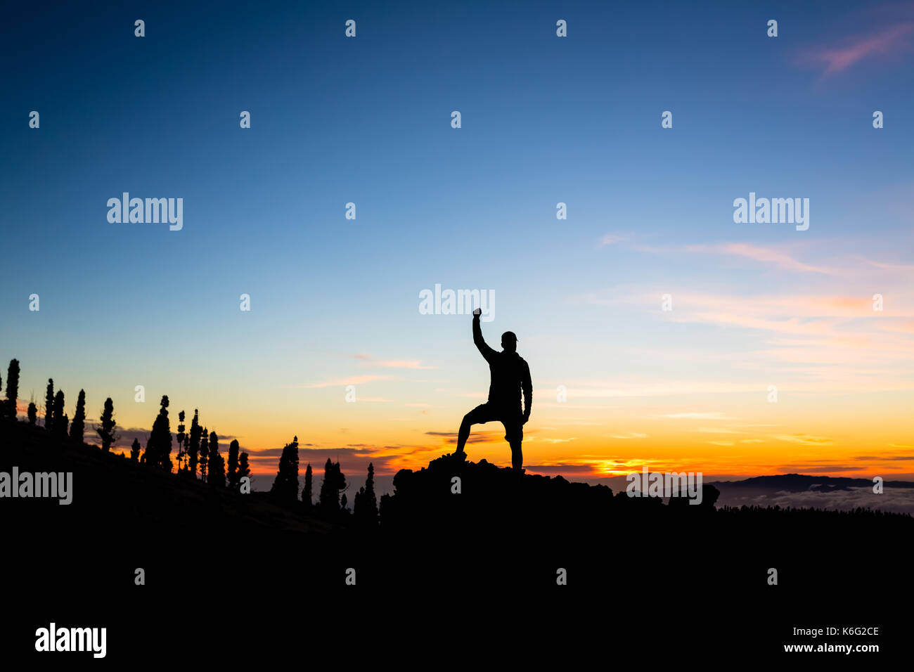 Mann feiern Sonnenuntergang in den Bergen mit ausgestreckten Armen. Trail Runner, Wanderer oder Bergsteiger mit erhobenen Händen erreicht ein Ziel auf einem Berg, enjo Stockfoto