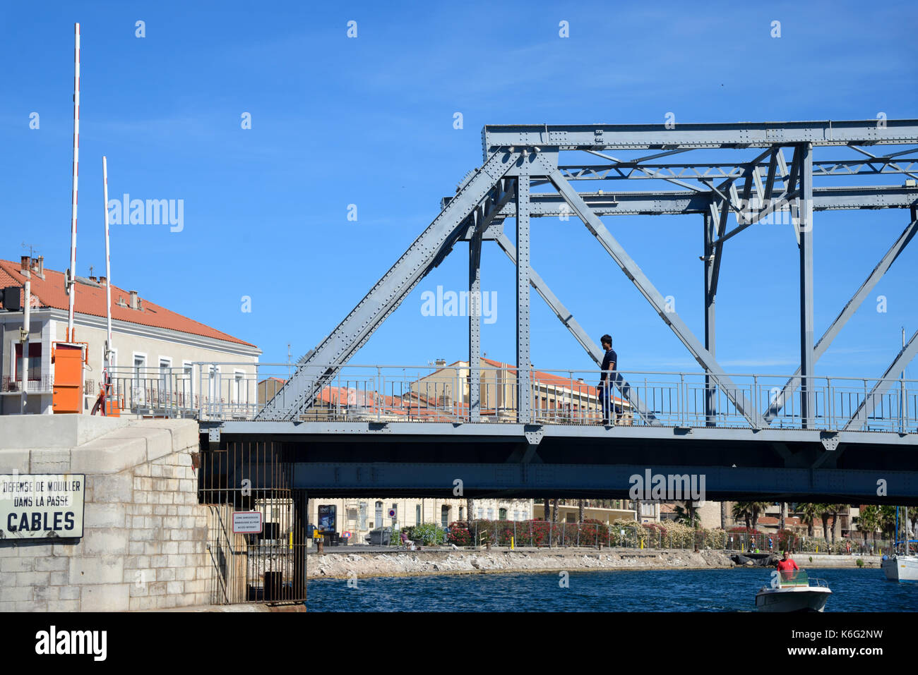 Mann, der über eine Box-Träger-Eiserne Brücke über den Royal Canal bei Sète oder Sete Herault Languedoc-Roussillon Frankreich geht Stockfoto