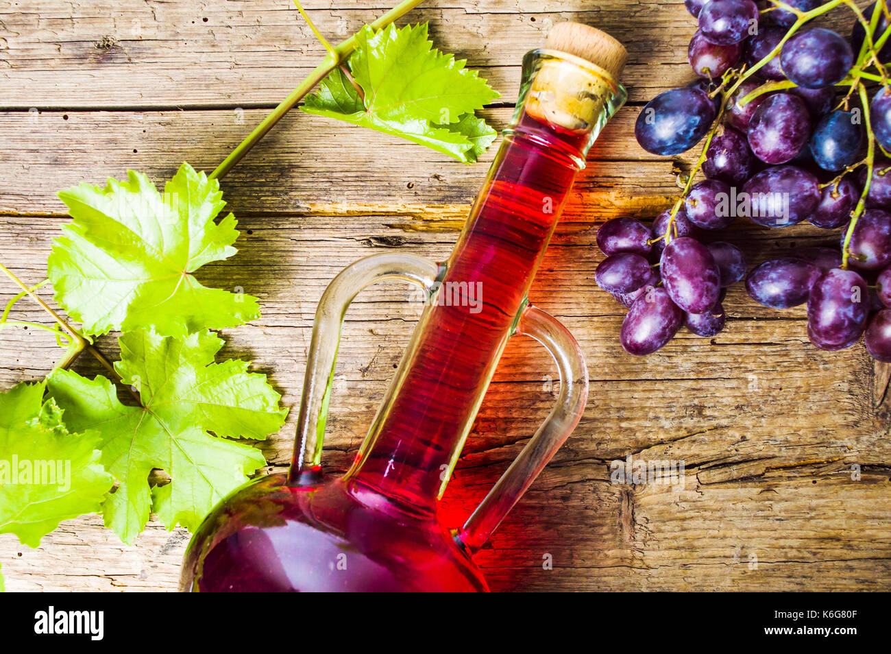 Rotwein mit Trauben auf einem rustikalen Holzmöbeln Hintergrund Stockfoto