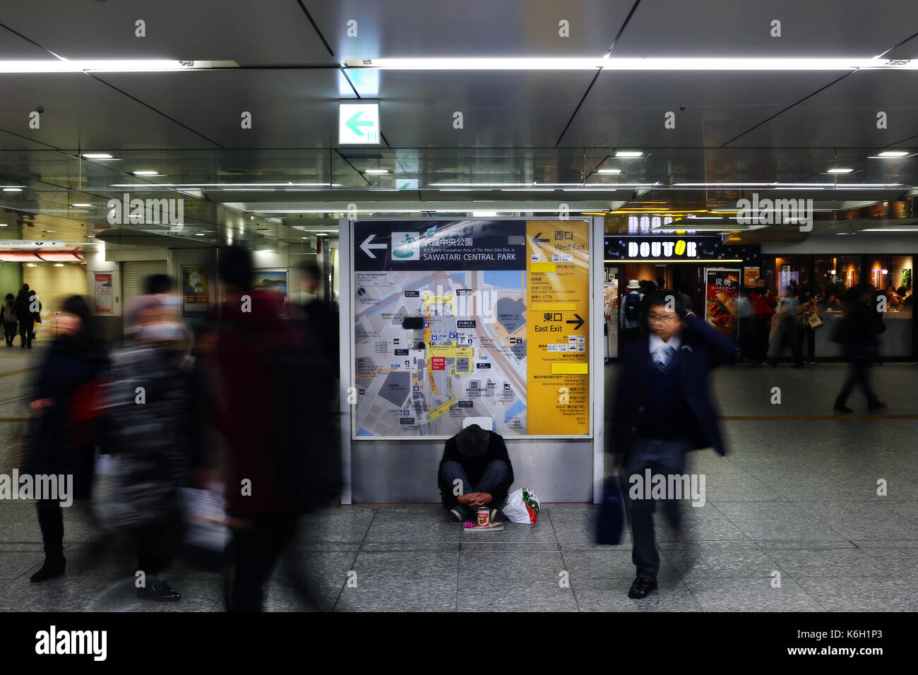 YOKOHAMA, Japan - Dezember 2016 - Nicht identifizierte Person sitzt in der Mitte der Yokohama Station, während die Durch sind Stockfoto