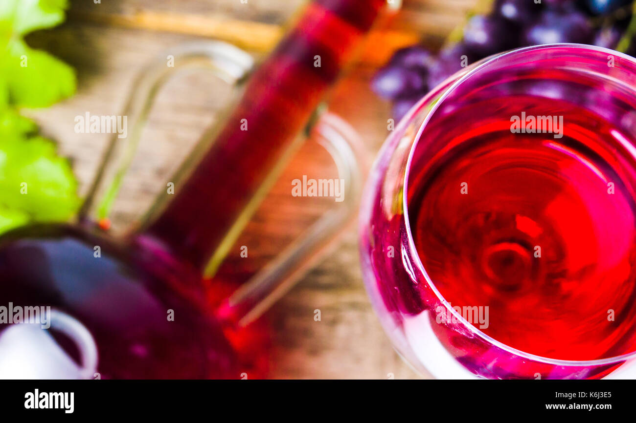 Glas Rotwein mit Trauben auf einem rustikalen Holzmöbeln Hintergrund Stockfoto