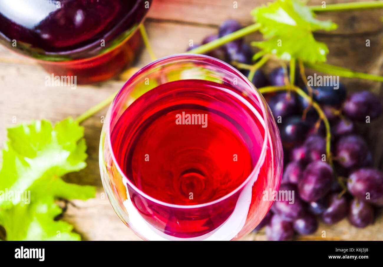 Glas Rotwein mit Trauben auf einem rustikalen Holzmöbeln Hintergrund Stockfoto